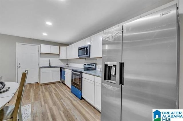 kitchen featuring appliances with stainless steel finishes, tasteful backsplash, sink, white cabinets, and light hardwood / wood-style floors