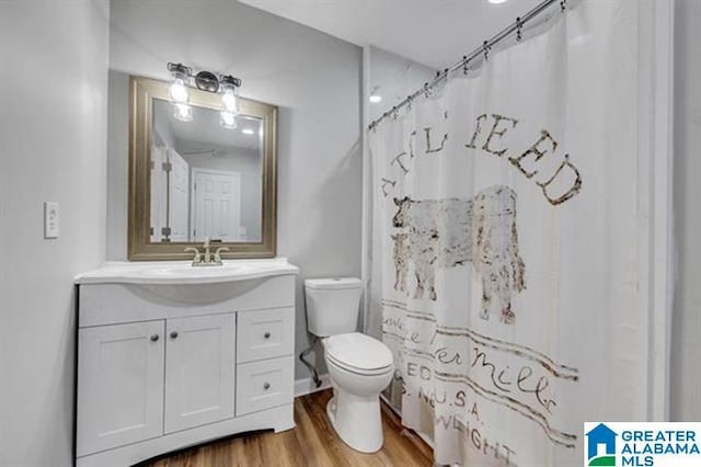 bathroom with wood-type flooring, walk in shower, vanity, and toilet