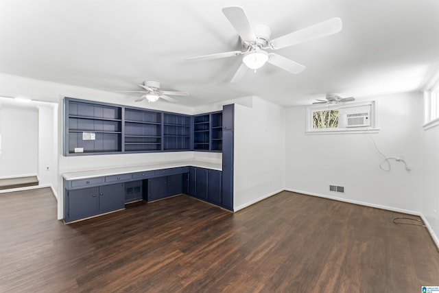 unfurnished office featuring dark wood-type flooring, a wall mounted AC, ceiling fan, and built in desk