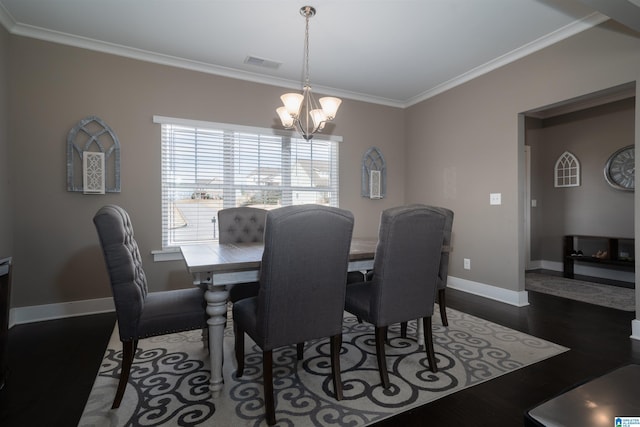 dining space featuring a notable chandelier, ornamental molding, and dark wood-type flooring