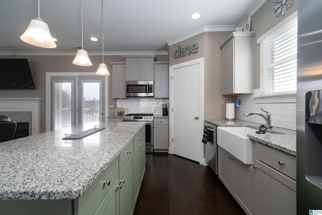 kitchen featuring hanging light fixtures, appliances with stainless steel finishes, dark wood-type flooring, a kitchen island, and decorative backsplash