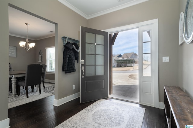 foyer entrance featuring dark hardwood / wood-style floors, crown molding, and an inviting chandelier