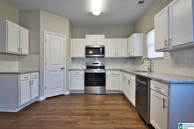 kitchen featuring light stone countertops, dark wood-type flooring, white cabinetry, stainless steel appliances, and sink