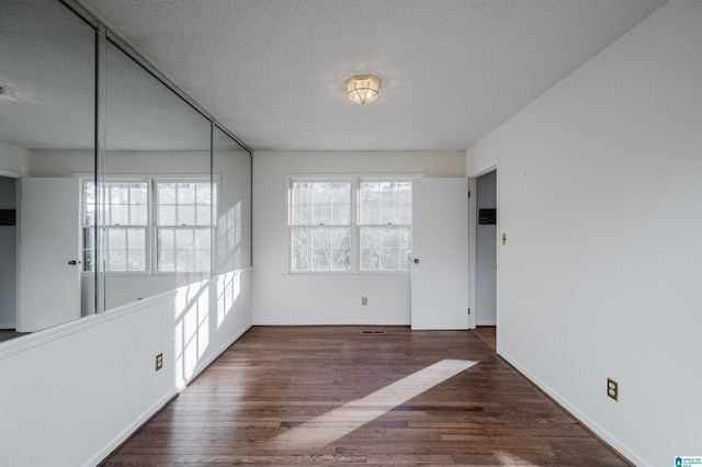 spare room with dark wood-type flooring and a textured ceiling