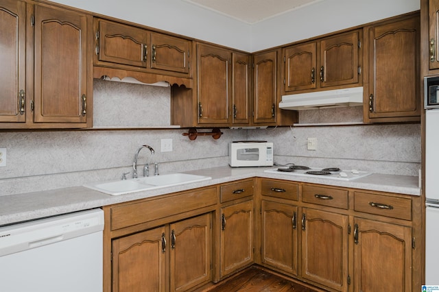 kitchen with sink, white appliances, dark hardwood / wood-style floors, and tasteful backsplash