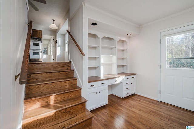 staircase with wood-type flooring, ceiling fan, and ornamental molding