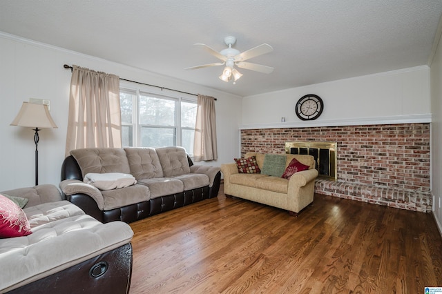 living room featuring ceiling fan, a brick fireplace, hardwood / wood-style floors, and a textured ceiling