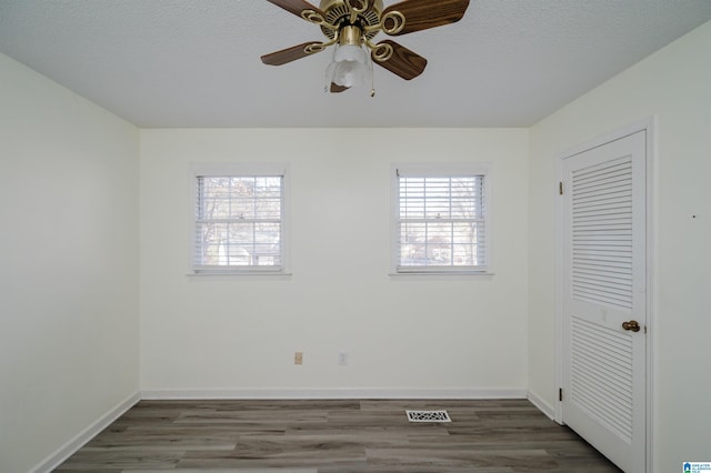 unfurnished bedroom featuring ceiling fan, hardwood / wood-style floors, a closet, and a textured ceiling