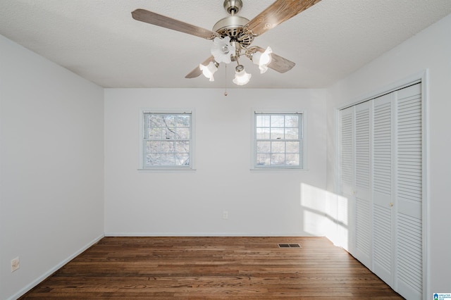 unfurnished bedroom with ceiling fan, a textured ceiling, dark hardwood / wood-style floors, and a closet