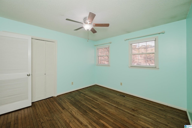 unfurnished bedroom featuring ceiling fan, dark hardwood / wood-style floors, and a closet