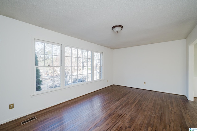 spare room featuring a textured ceiling and dark hardwood / wood-style floors