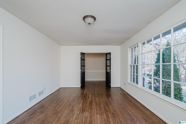 spare room with a textured ceiling and dark hardwood / wood-style flooring