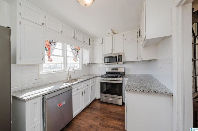 kitchen with dark wood-type flooring, sink, appliances with stainless steel finishes, light stone countertops, and white cabinets