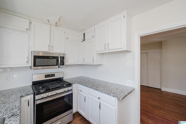 kitchen with white cabinetry, light stone counters, dark wood-type flooring, and stainless steel appliances