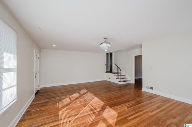 empty room featuring wood-type flooring and an inviting chandelier