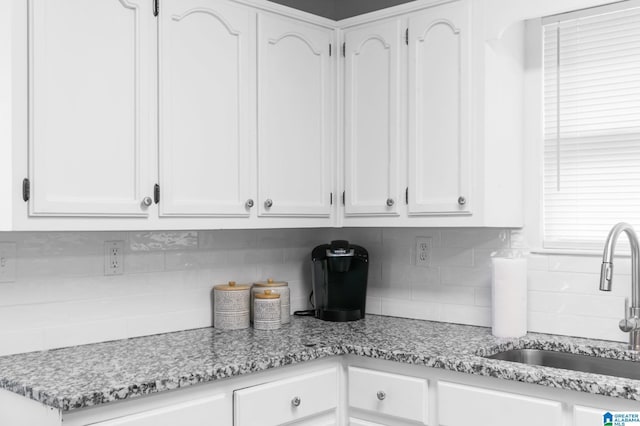 kitchen with sink, white cabinets, tasteful backsplash, and light stone countertops