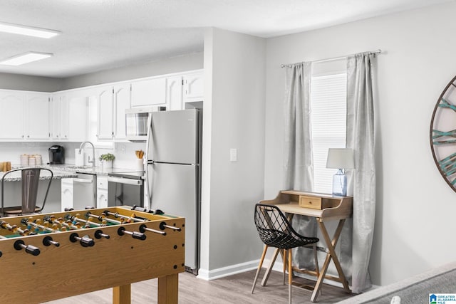 game room featuring sink, light hardwood / wood-style floors, and a textured ceiling