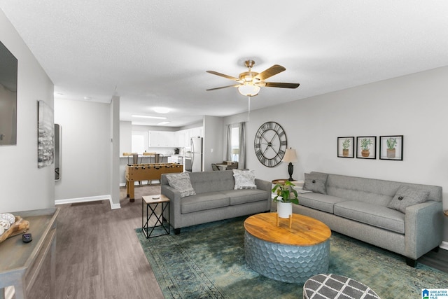 living room featuring ceiling fan, a textured ceiling, and dark hardwood / wood-style flooring