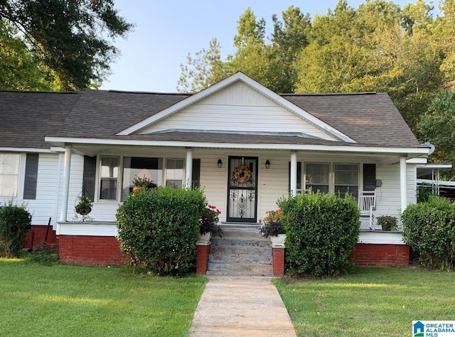 view of front of property featuring a porch, roof with shingles, and a front yard