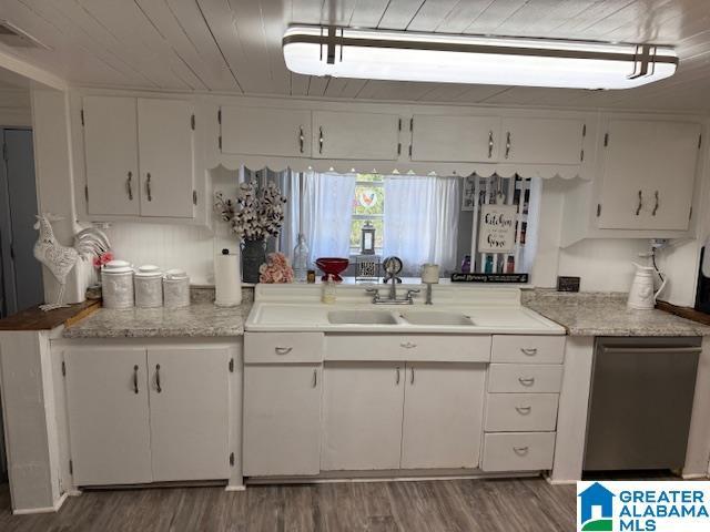 kitchen featuring light countertops, stainless steel dishwasher, a sink, and white cabinetry