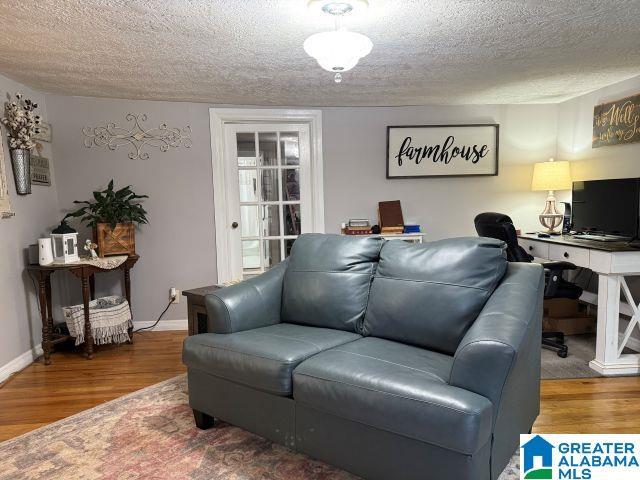 living room featuring a textured ceiling, wood finished floors, and baseboards