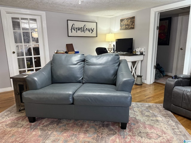 living room featuring a textured ceiling, wood finished floors, and baseboards