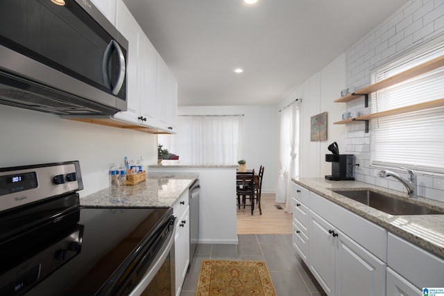 kitchen featuring light stone counters, sink, white cabinetry, and appliances with stainless steel finishes