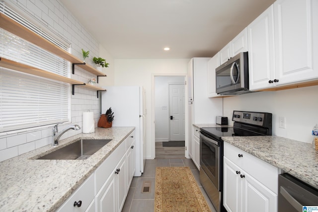 kitchen featuring sink, white cabinetry, light tile patterned floors, light stone countertops, and stainless steel appliances