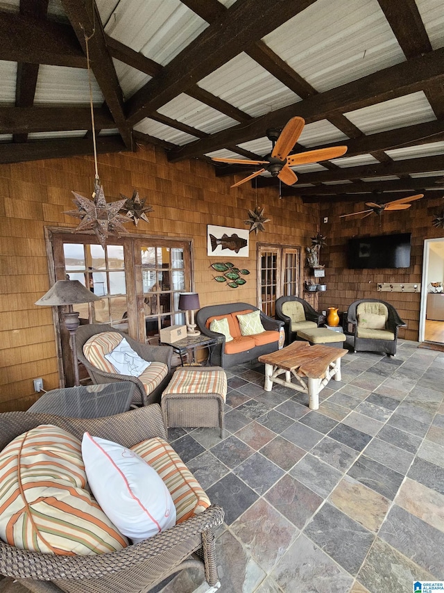 living room with beamed ceiling, ceiling fan, and wooden walls