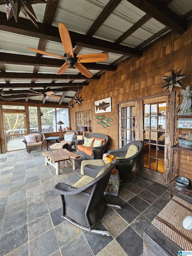 living room featuring vaulted ceiling, wooden walls, and ceiling fan