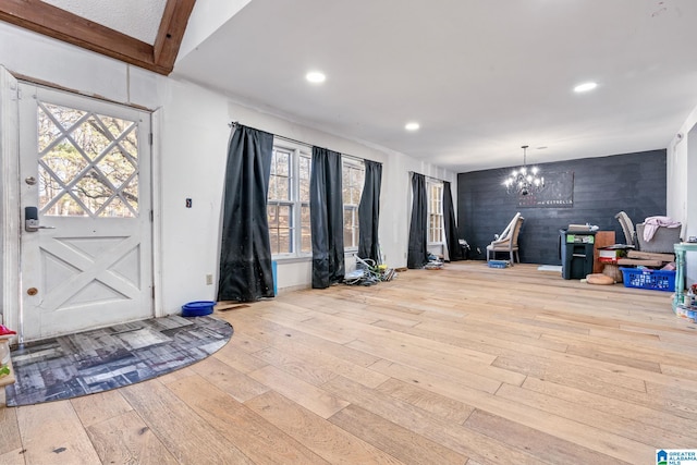 foyer entrance with lofted ceiling, an inviting chandelier, and light hardwood / wood-style floors