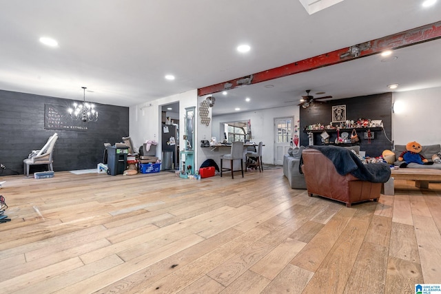 living room featuring ceiling fan with notable chandelier and light hardwood / wood-style flooring