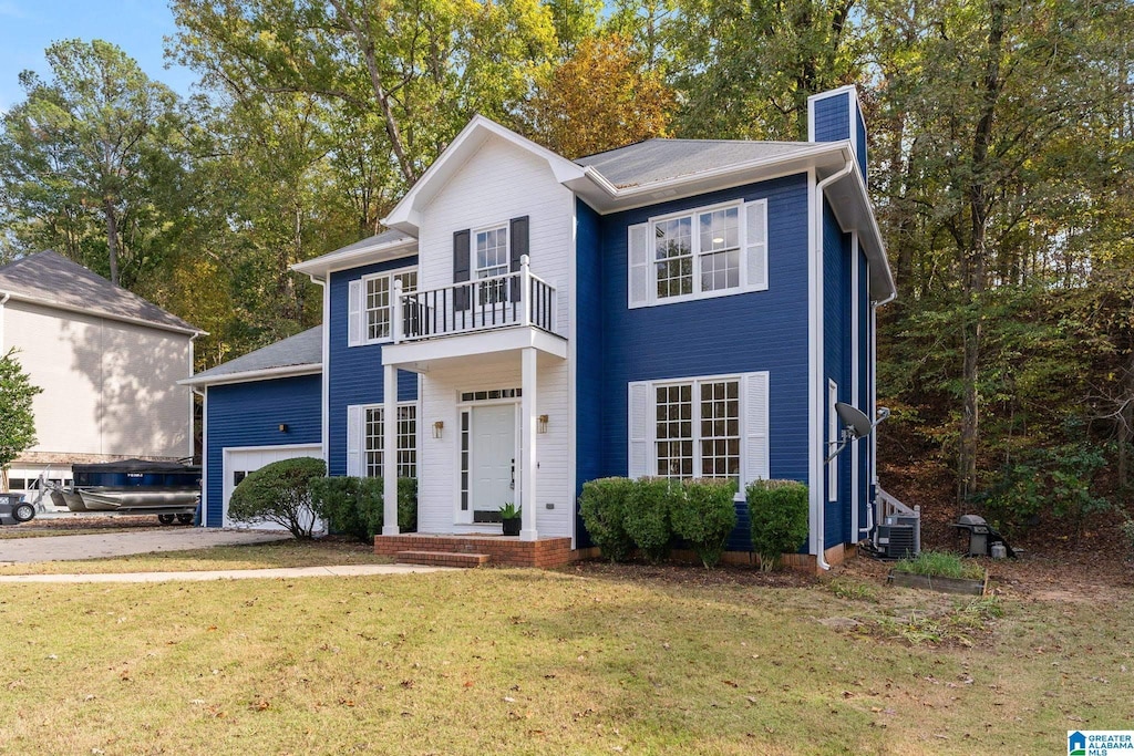 view of front of home featuring a balcony, a front yard, and a garage