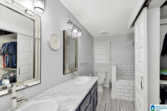 bathroom featuring tiled bath, vanity, and toilet