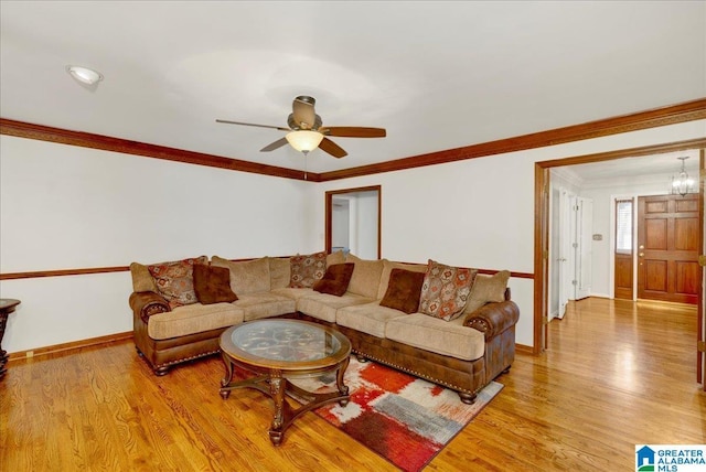 living room with ceiling fan with notable chandelier, crown molding, and light hardwood / wood-style floors