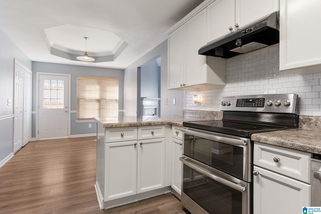 kitchen with double oven range, kitchen peninsula, white cabinetry, and a raised ceiling