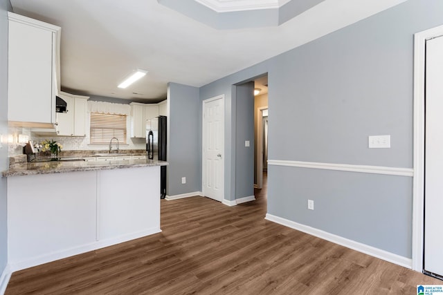 kitchen with stone counters, stove, kitchen peninsula, sink, and white cabinetry