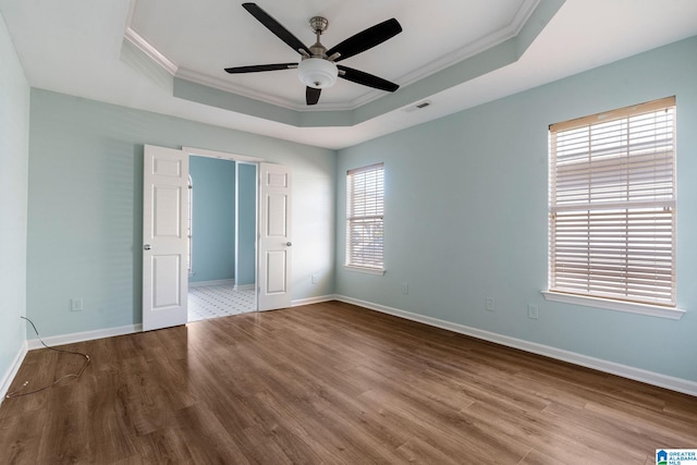 unfurnished bedroom with a raised ceiling, ceiling fan, crown molding, and hardwood / wood-style floors