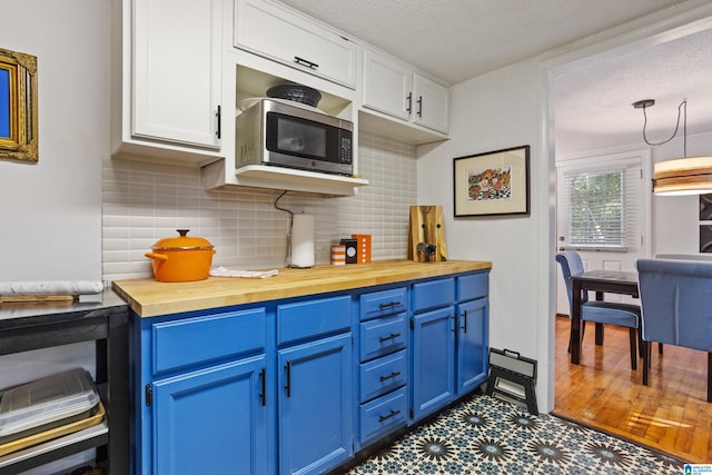 kitchen with a textured ceiling, wooden counters, white cabinetry, tasteful backsplash, and blue cabinetry