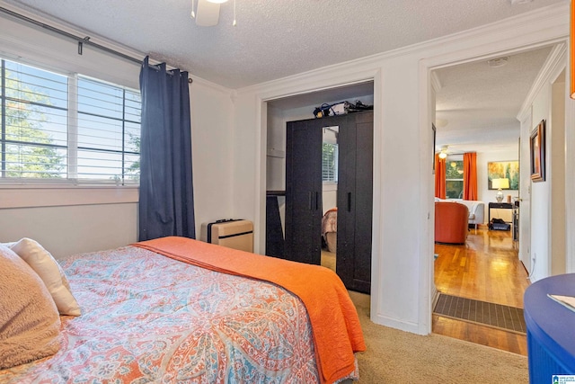 bedroom featuring ceiling fan, crown molding, a textured ceiling, and light hardwood / wood-style flooring