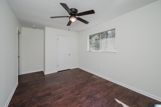 unfurnished bedroom with ceiling fan, a textured ceiling, and dark hardwood / wood-style flooring