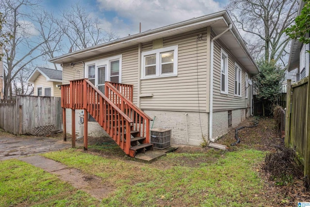 rear view of house featuring a yard, central air condition unit, and a deck