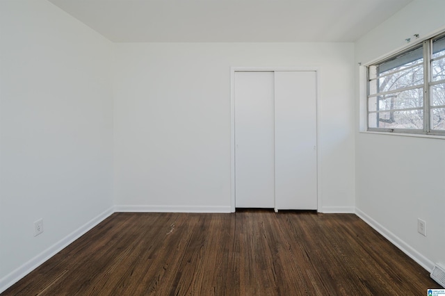 unfurnished bedroom featuring a closet and dark hardwood / wood-style flooring