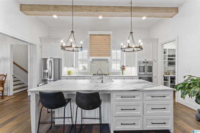 kitchen with stainless steel appliances, a kitchen island, hanging light fixtures, and white cabinets