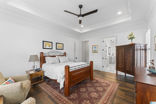 bedroom with dark wood-type flooring, ornamental molding, a raised ceiling, and ensuite bathroom