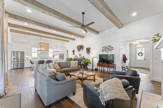 living room with beamed ceiling, dark hardwood / wood-style flooring, and ceiling fan with notable chandelier