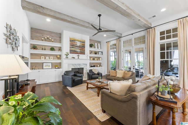 living room with beam ceiling, dark hardwood / wood-style floors, built in features, ceiling fan, and a premium fireplace