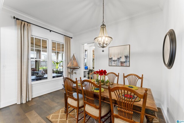 dining space featuring dark wood-type flooring, ornamental molding, and an inviting chandelier