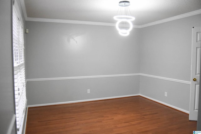 empty room featuring wood-type flooring, an inviting chandelier, and ornamental molding