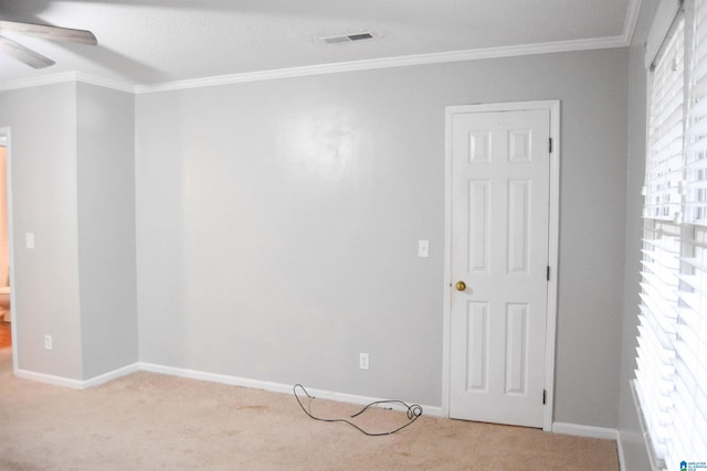 carpeted empty room featuring ceiling fan, a wealth of natural light, and crown molding